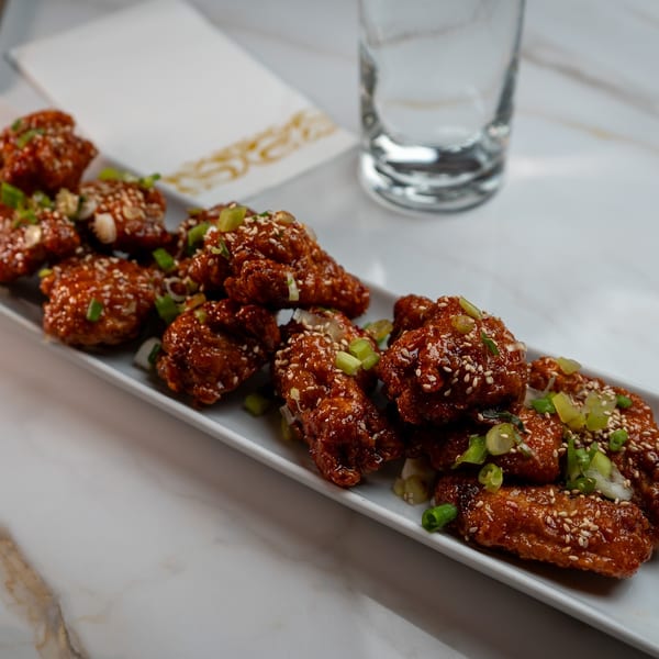 Crispy Korean fried chicken wings, glazed with sweet and spicy sauce, topped with sesame seeds and scallions.